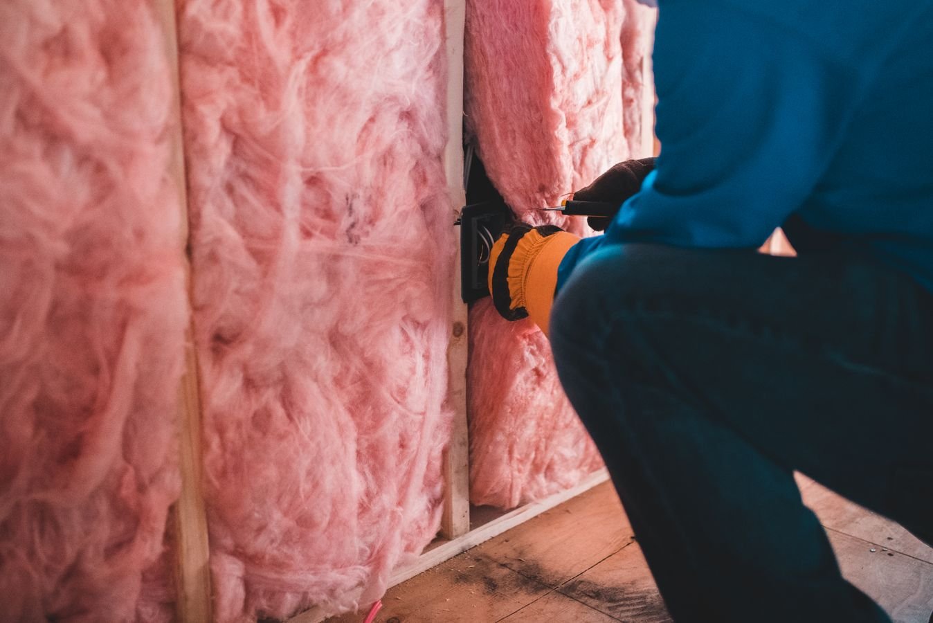 Ouvrier posant des rouleaux de laine de roche pour l'isolation des combles perdus