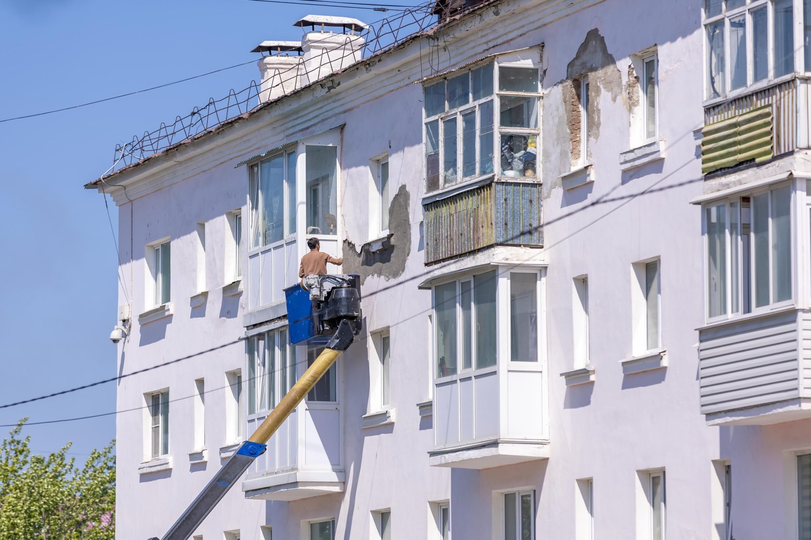 Ouvrier réalisant un ravalement de façade depuis une nacelle élévatrice